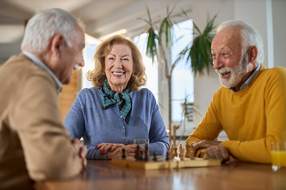 Happy senior friends playing chess together in a warm setting
