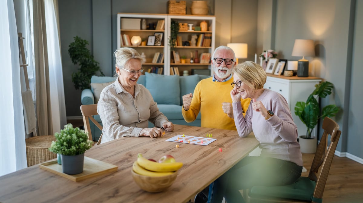 Group of seniors playing board games together having fun in a home-like setting