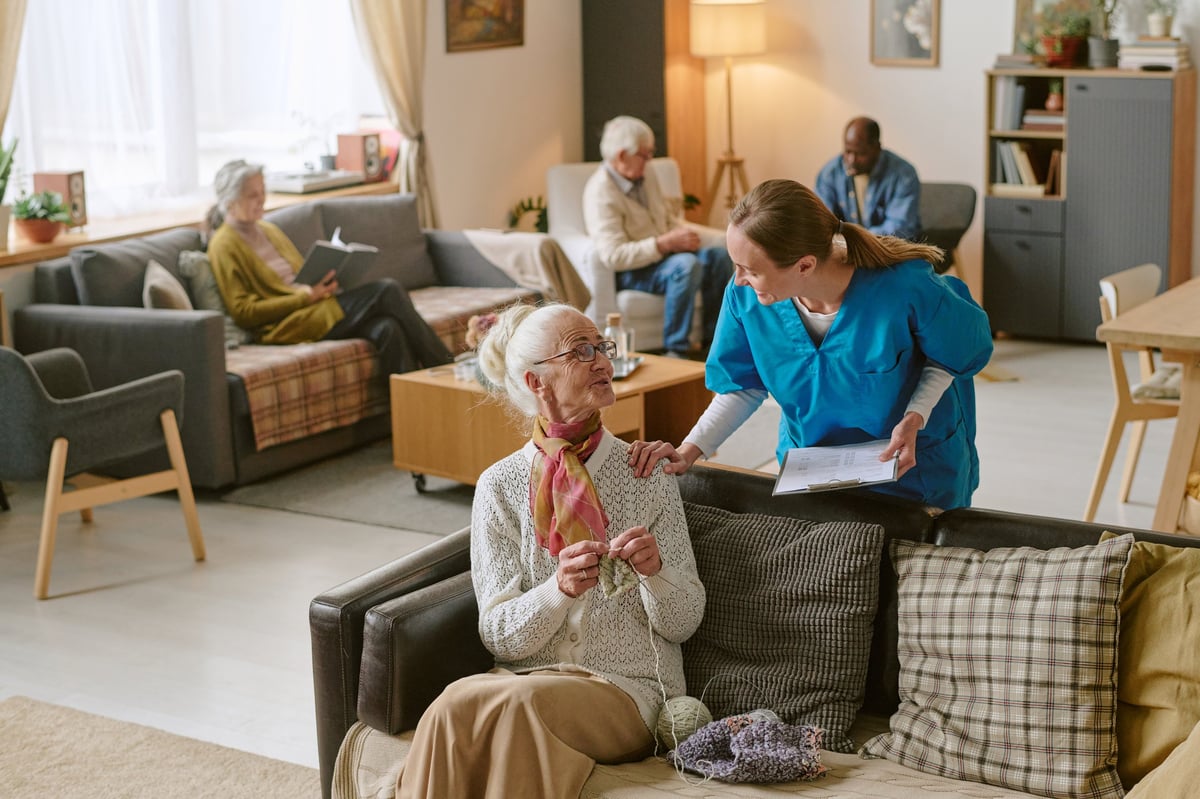Nurse communicating with senior woman who is sharing progress in crocheting