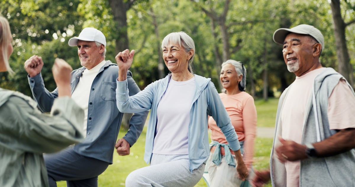Senior exercise class outdoors with personal trainer, active lifestyle for elderly